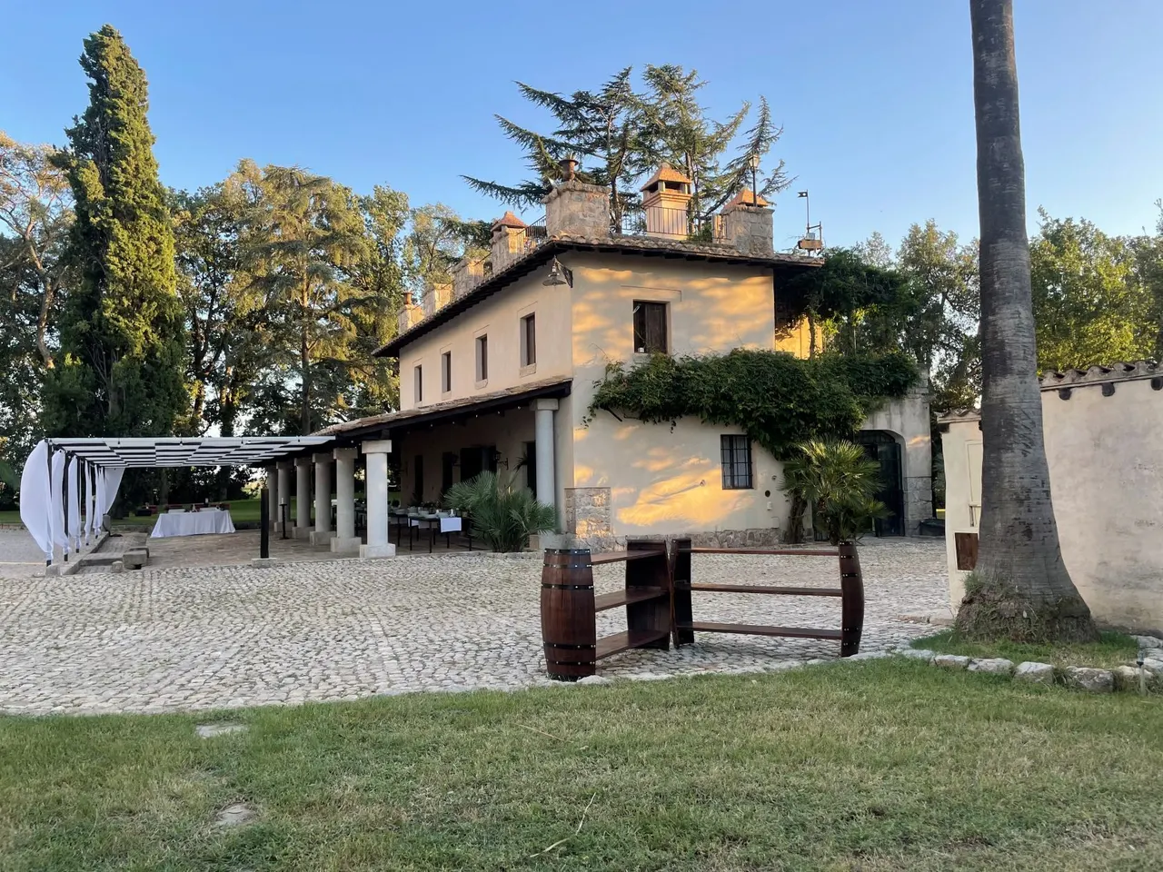Il portico della dimora al tramonto, con le tende bianche e i tavoli apparecchiati